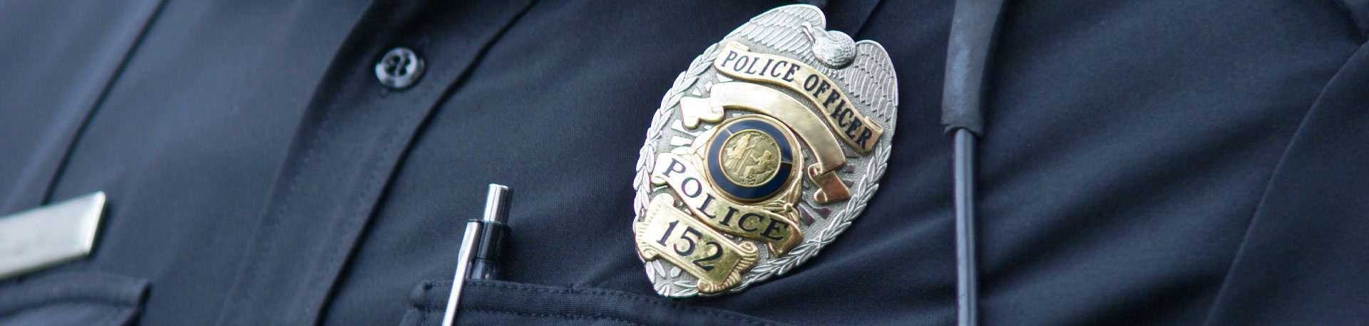 Close-up of police officer badge worn on officer's black shirt.